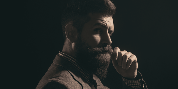 Stylish man with a well-groomed beard, wearing a suit and looking thoughtful. Highlighting the confidence of a well-maintained beard, debunking myths about beard growth.