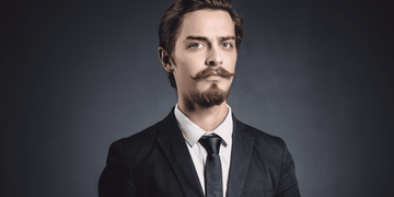 Man with an Anchor Beard in a Suit - A professional portrait of a man showcasing a well-groomed anchor beard, featuring a pointed chin beard and a disconnected mustache, perfect for modern men's grooming and style.