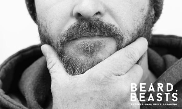 Close-up image of a man holding his beard, showing discomfort and wondering why does my beard hurt. The image highlights concerns about beard pain.