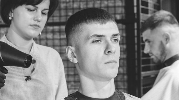 Man receiving a crew cut hairstyle at a barbershop, reflecting the crew cut vs buzz cut debate