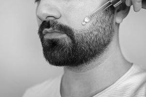 Man applying beard oil to enhance thin beard growth and texture