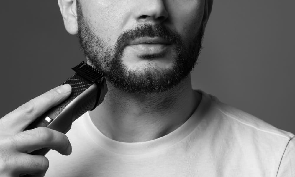 Man trimming his beard with an electric trimmer for precise grooming