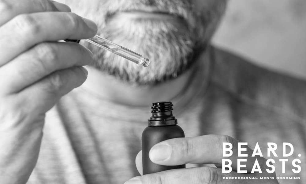 Man applying beard oil with a dropper—demonstrating proper beard hydration for softness, health, and grooming discipline.