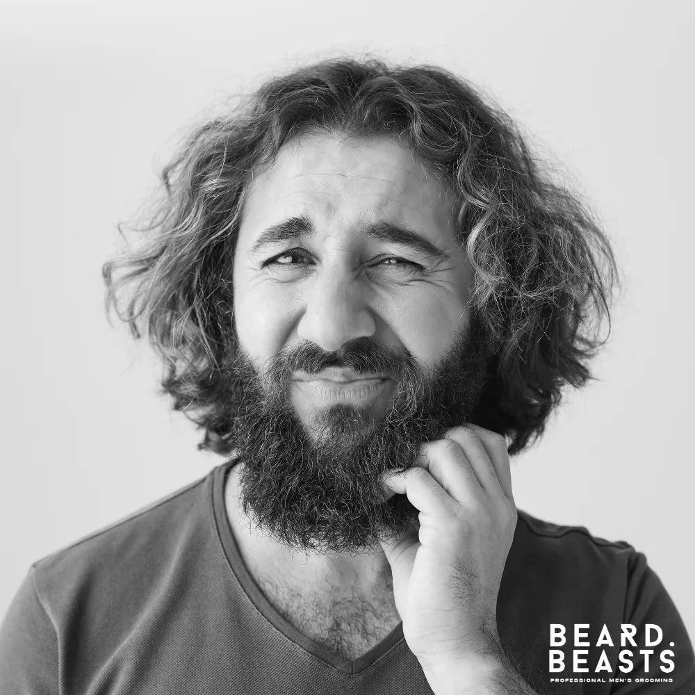 Man scratching his beard due to itch and irritation, showing early symptoms of beard dandruff.