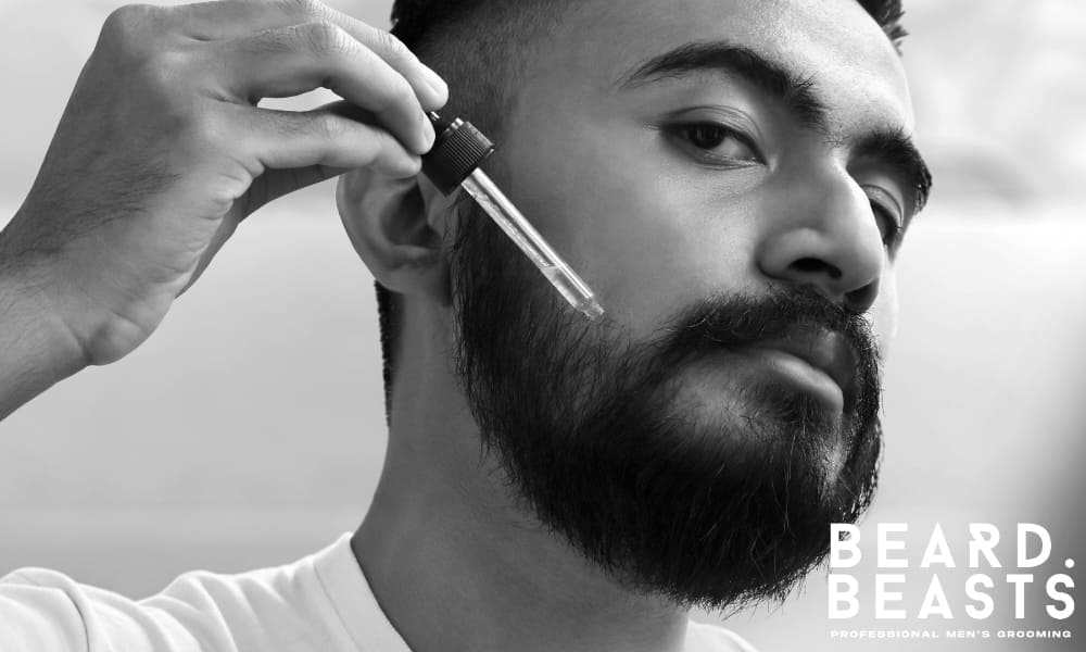 Man applying beard oil with dropper to treat dry skin under beard and improve hydration