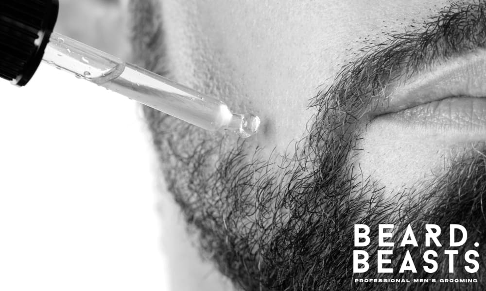 Close-up of a man applying beard oil with a dropper, illustrating a common mistake in beard care: over-application, which can hinder the oil’s effectiveness and slow down visible results.