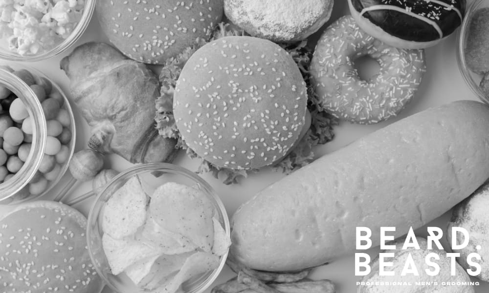 Unhealthy fast food including chips, soda, pizza, popcorn, and a burger—examples of foods that can hinder beard growth.