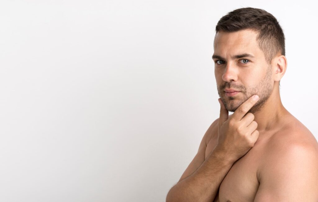 A man touches his chin thoughtfully, showcasing his clean, fresh face. His expression reflects consideration of his combination skin type as part of his routine.