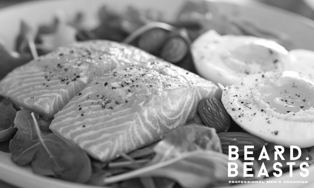 Plate of biotin-rich foods including salmon, soft-boiled eggs, almonds, and leafy greens—natural sources that support healthy beard growth.