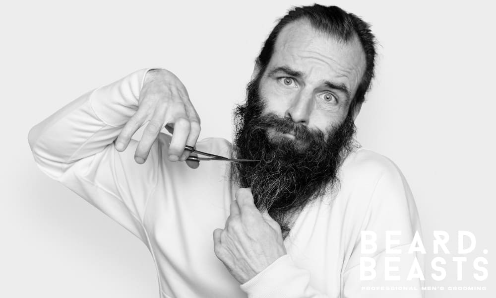 Man awkwardly trimming beard with scissors, showing common grooming mistakes