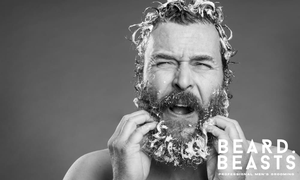 Man washing his beard with hair shampoo, highlighting a common beard care mistake.