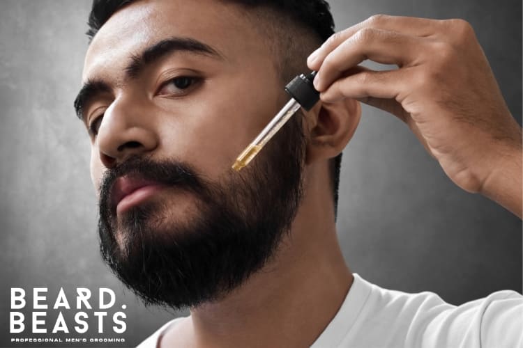 Close-up of a man applying beard oil to his rough beard, emphasizing proper grooming techniques for softer and healthier facial hair, with the Beard Beasts logo in the corner.