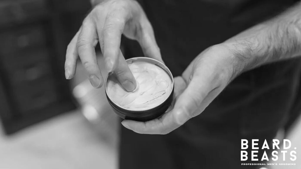 Close-up of a man scooping styling cream from a tin — representing proper use and application tips for men’s hair products.