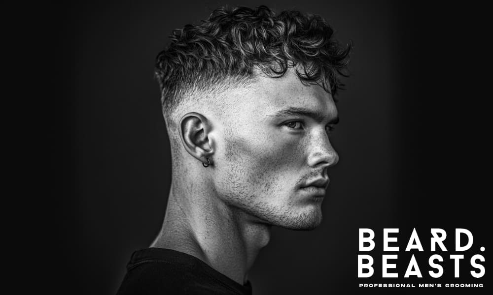Side profile of a man with wavy hair and a textured medium-length cut, showing clean sides and natural volume.