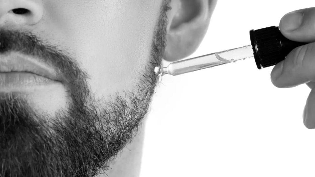 Man applying beard oil with dropper to moisturize and condition beard hair
