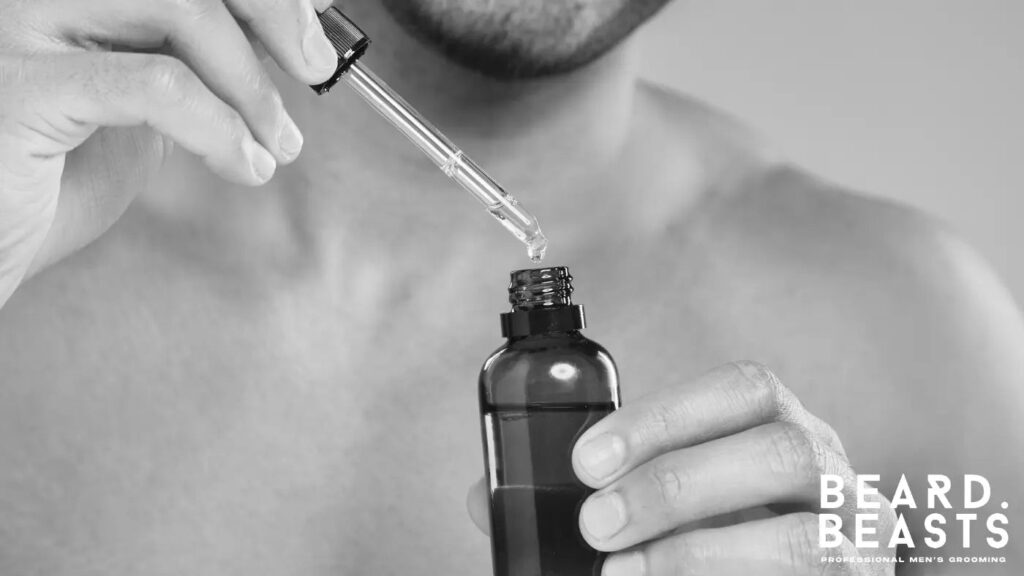 Man using a dropper to apply beard oil from a brown bottle for hydration and beard care