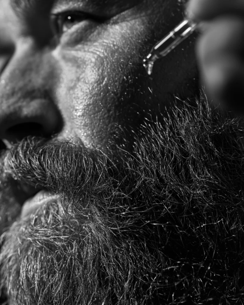 Close up of a man applying almond oil to a coarse beard to soften facial hair and improve beard condition