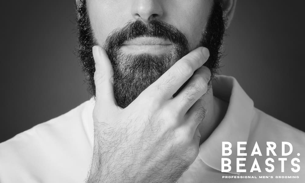 Close-up of a bearded man touching his beard, highlighting growth and grooming care