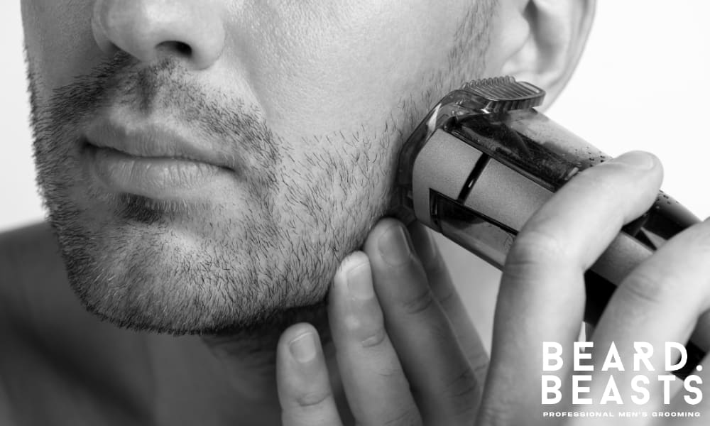 Close-up of a man trimming his stubble with a precision trimmer, maintaining even length and clean lines for a well-groomed designer stubble style.