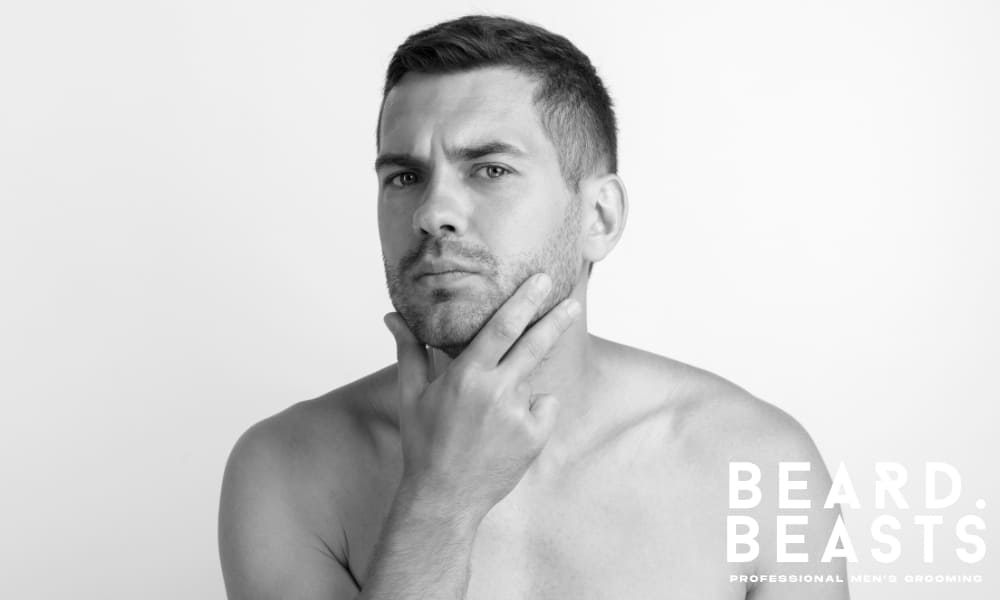 Man evaluating the shape and appearance of his facial hair while posing in front of the camera.