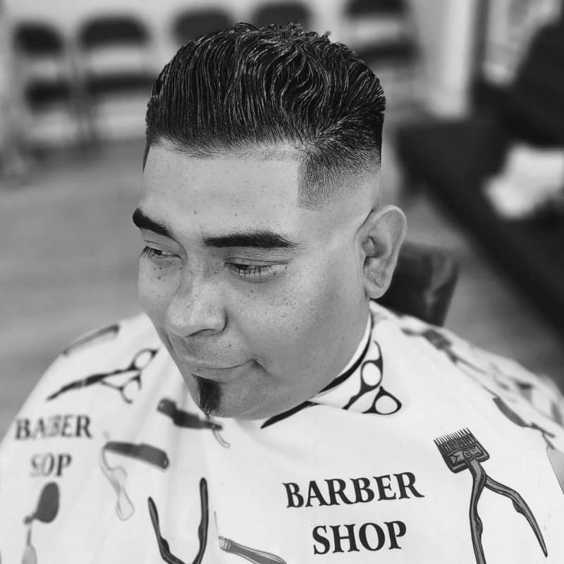 Man with a defined soul patch beard and styled pompadour haircut, captured in a barbershop setting—showcasing a clean, modern grooming look.