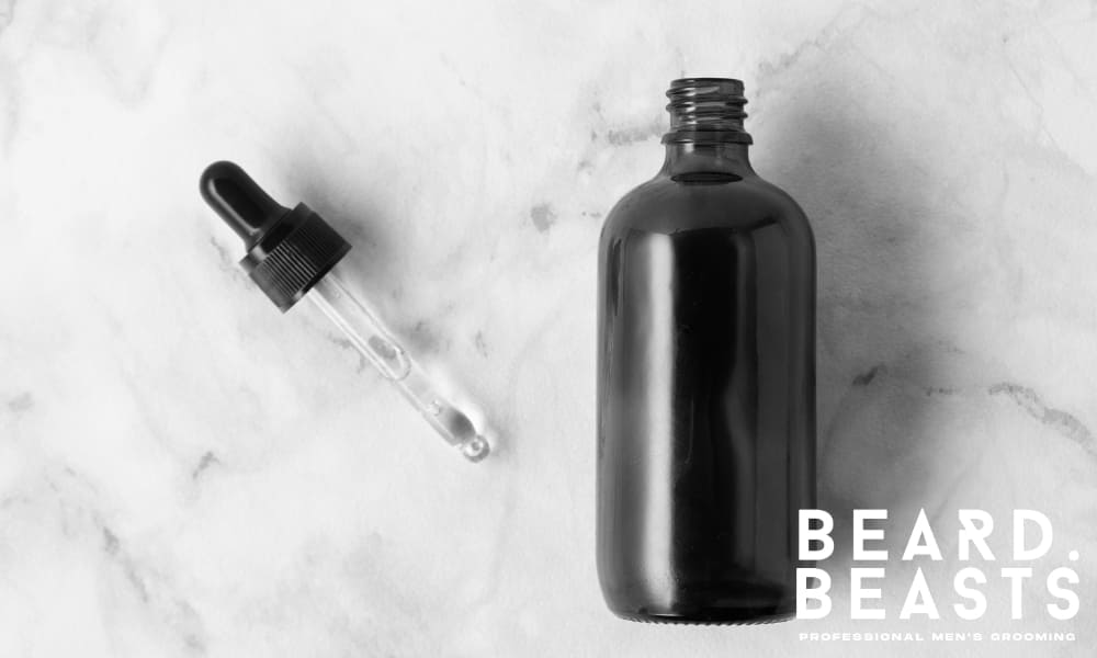 Beard oil dropper and amber bottle on marble surface – perfect for daily grooming routine