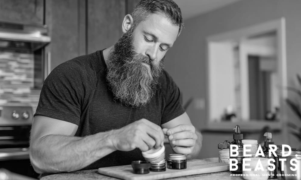 bearded man making homemade beard balm in a modern kitchen using natural ingredient