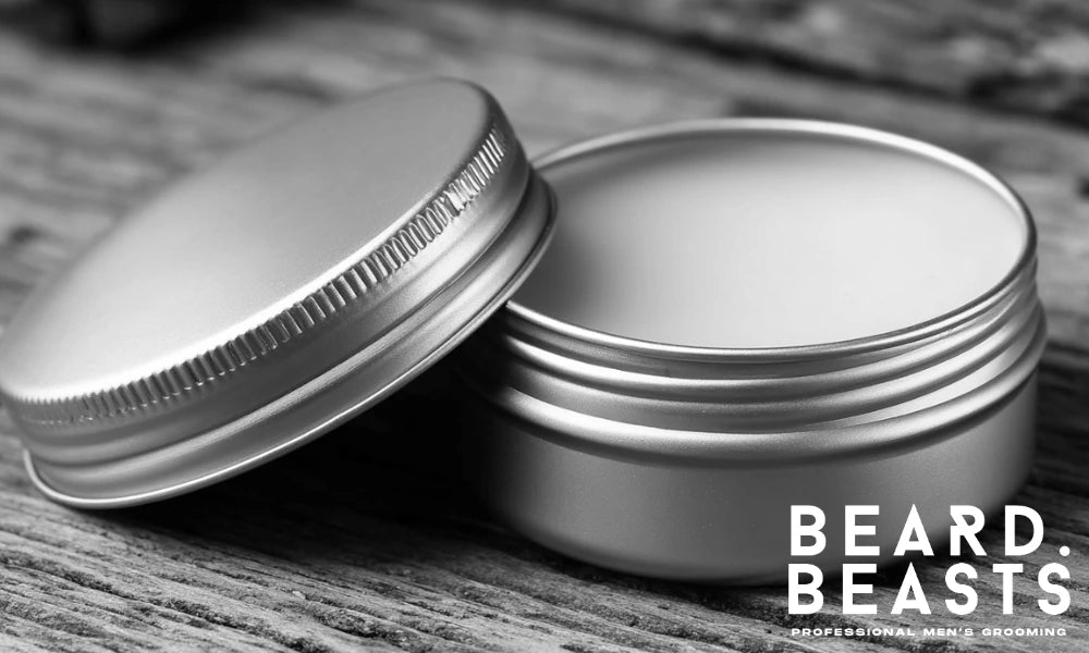 Close-up of a small metal tin filled with homemade beard butter, opened on a rustic wooden surface.