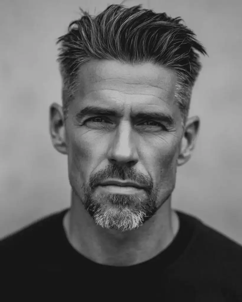 Portrait of a mature man wearing an extended goatee, featuring clean-shaven cheeks and a structured chin to elongate a round face.