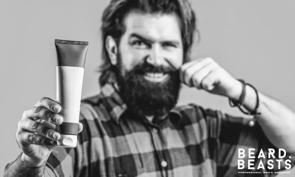 Bearded man holding beard conditioner to restore softness, reduce tangles, and improve beard manageability after washing.