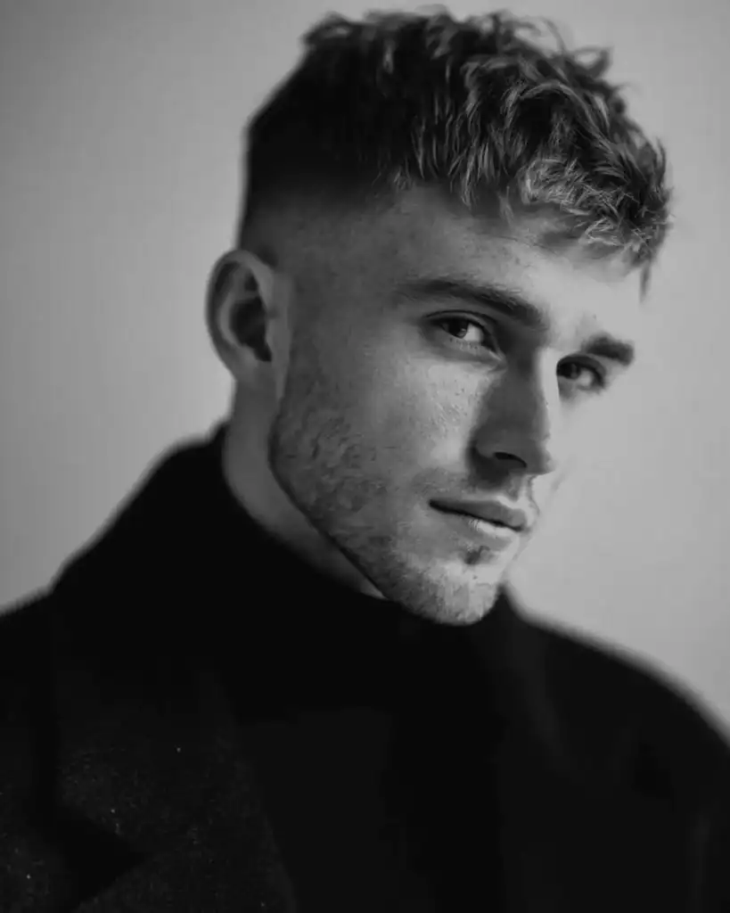 Model with a high skin fade styling a sharp number 2 beard (6mm heavy stubble