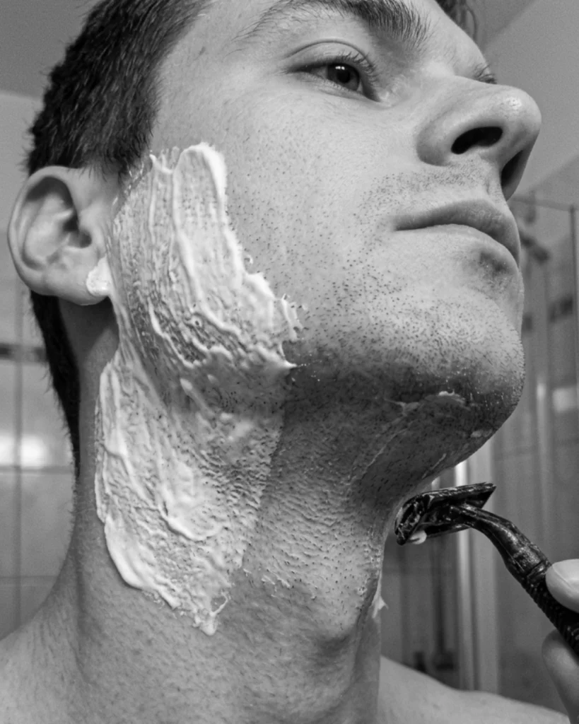 Man shaving his neck where the shaving cream has thinned out, leaving part of the skin with less protection from the razor