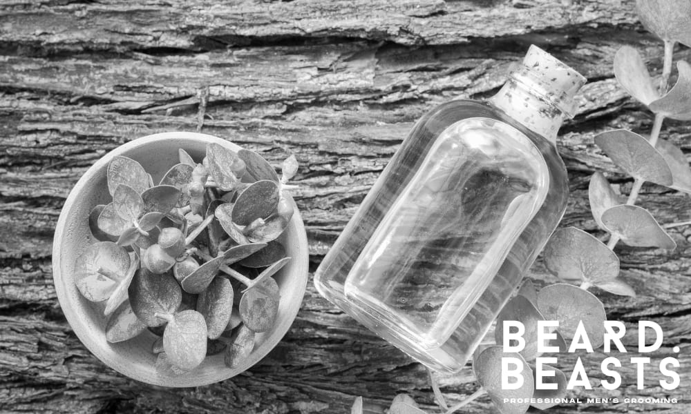 Bottle of eucalyptus oil and fresh leaves on wood—used to highlight the benefits of eucalyptus oil in beard care routines