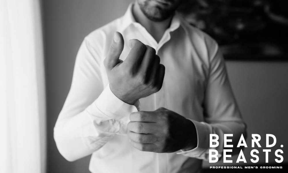 Man adjusting the cuff of a white dress shirt, showcasing proper sleeve length and fit—demonstrating how a dress shirt should fit with precision and polish.