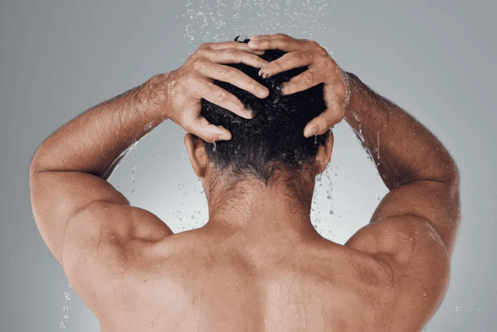 Man washing his hair in shower rinsing out styling product