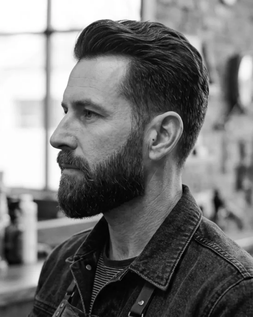 medium boxed beard with tapered sides in barbershop setting, side profile view