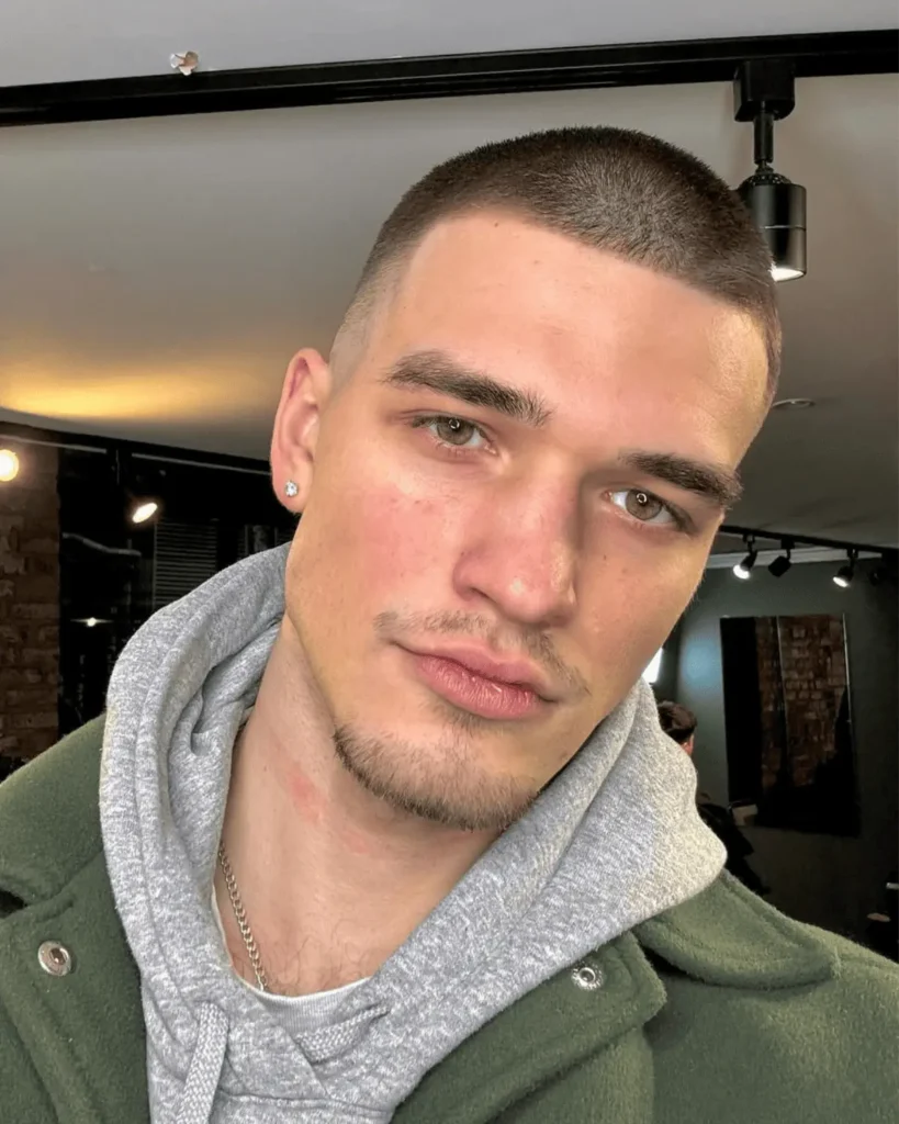 a man in a barbershop after getting a number 4 buzz cut fade haircut