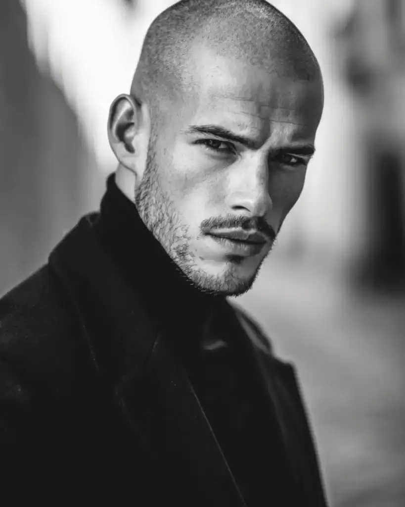 Number 2 buzz cut on a man with a sharp hairline and light stubble, showing a clean 6mm buzz cut that highlights head shape and facial structure