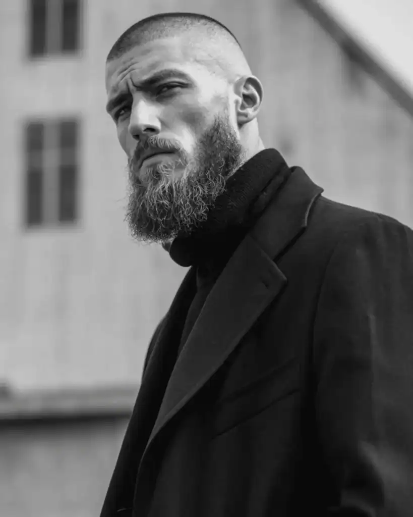 Number 2 buzz cut with fade on a man wearing a full beard, showing tight faded sides and a clean 6mm buzz cut that sharpens facial structure