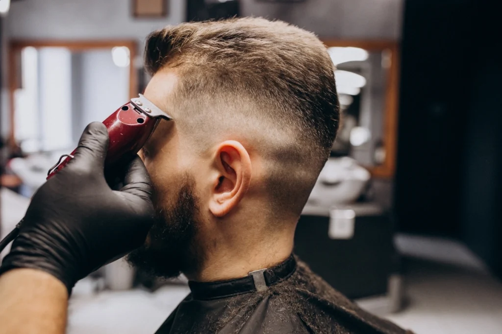Barber cutting a fade haircut with clippers in a barbershop
