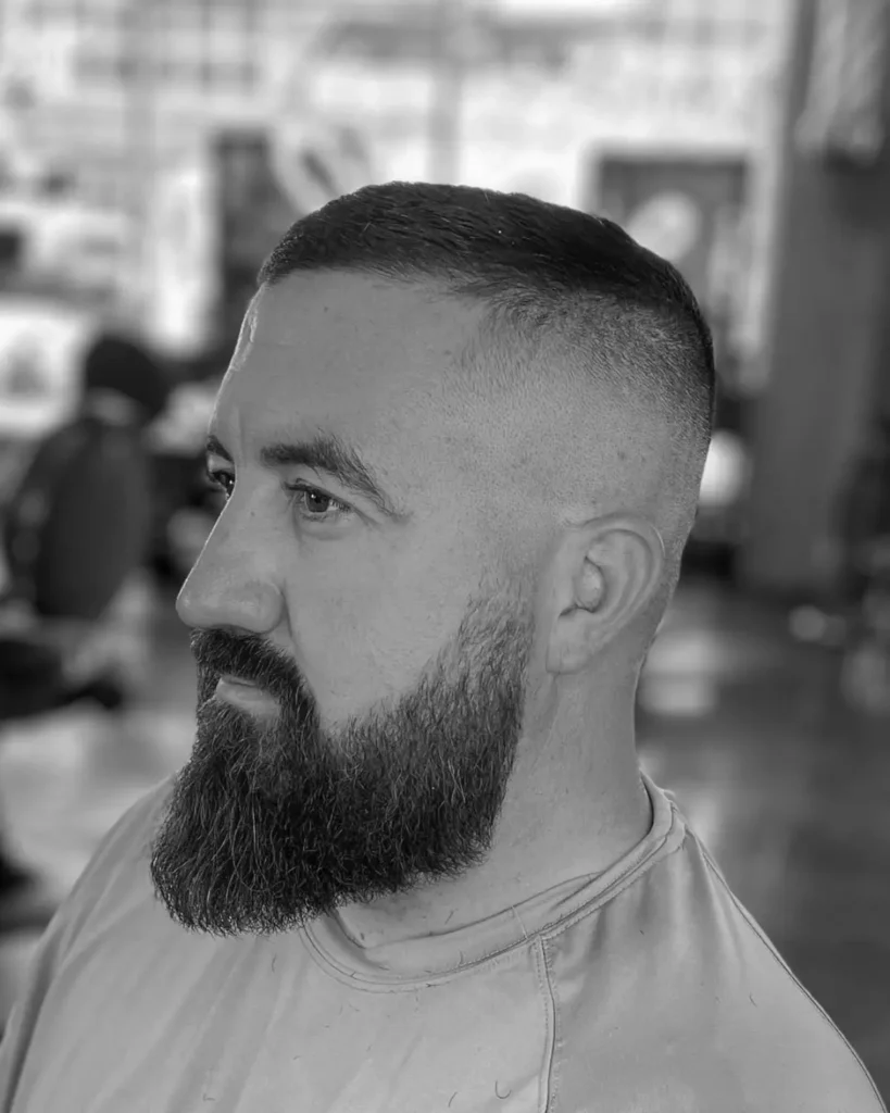 high and tight fade haircut with skin fade sides and full beard, side profile view