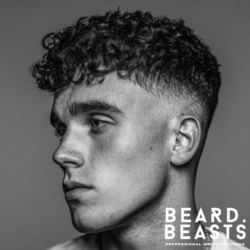 Men's curly fade haircut with a clean fade on the sides and textured, voluminous curls on top. Perfect for men with curly hair looking for a stylish, modern fade.