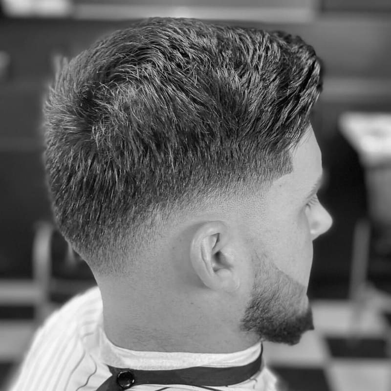 Men's low fade haircut with clean, blended sides and textured top, offering a sharp and polished look. Ideal for a sleek, professional appearance.
