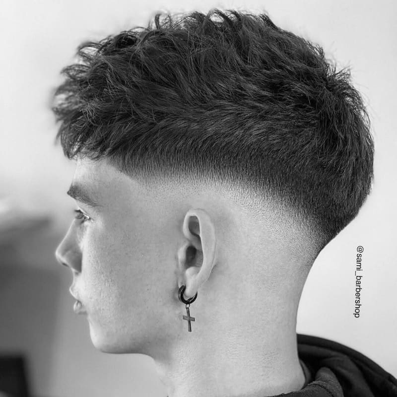 Men's mid fade haircut with textured top and clean, blended sides. Ideal for those seeking a sharp, modern fade with a balanced contrast.