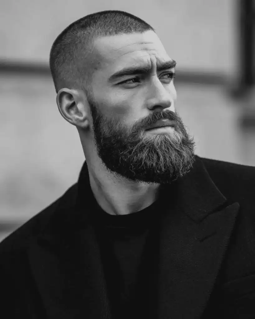 Number 3 buzz cut with full beard on a man, showing short 10mm buzzed hair paired with a thick, well-groomed beard