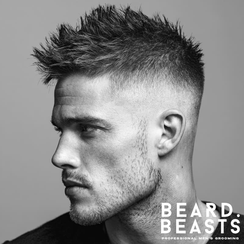 Man with a spiky short fade haircut and stubble, side profile showcasing textured styling.