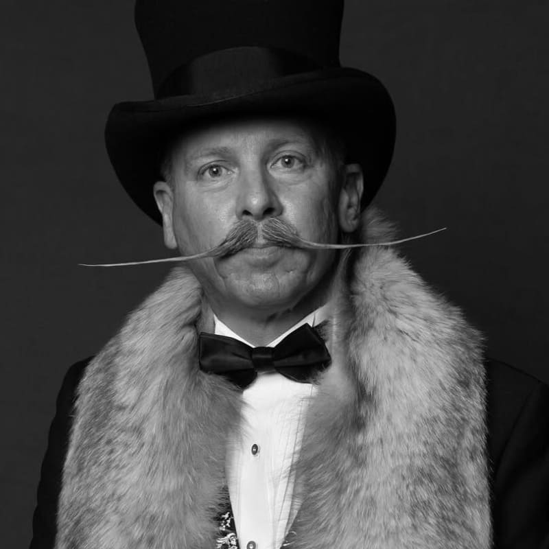 Styled portrait of a man with an exaggerated English mustache—one of the most defined types of mustaches, featuring long, straight horizontal ends.