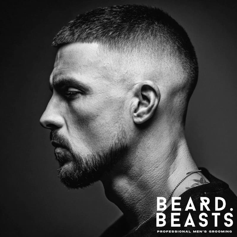 A profile shot of a man with a high fade and short hair on top, paired with a well-groomed beard for a sharp, clean, and modern look.