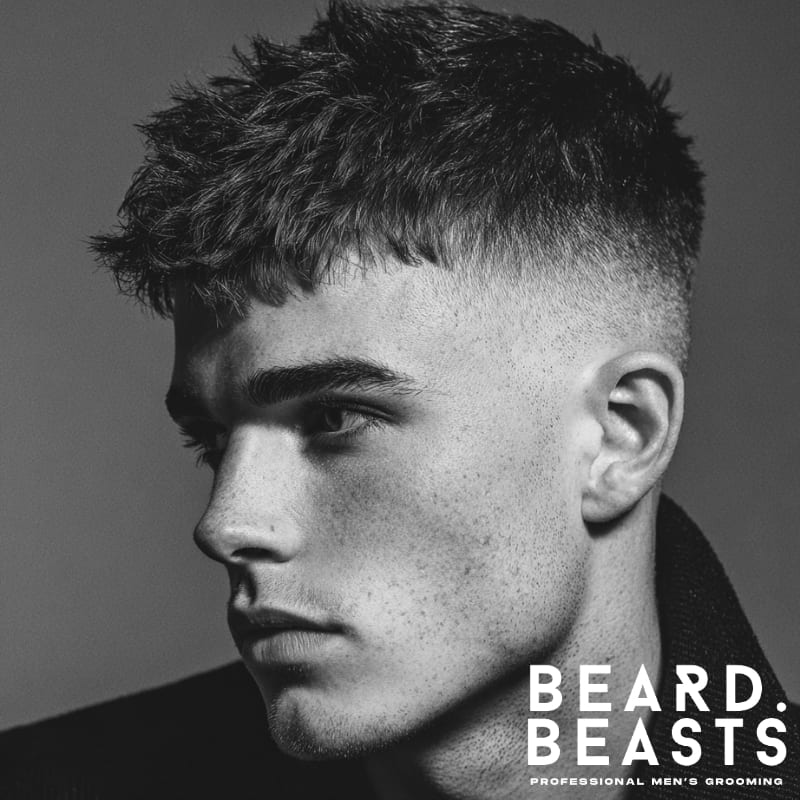 A profile shot of a man with a high fade and textured crop, showcasing short, choppy hair on top contrasted with a clean fade on the sides for a modern, stylish look.