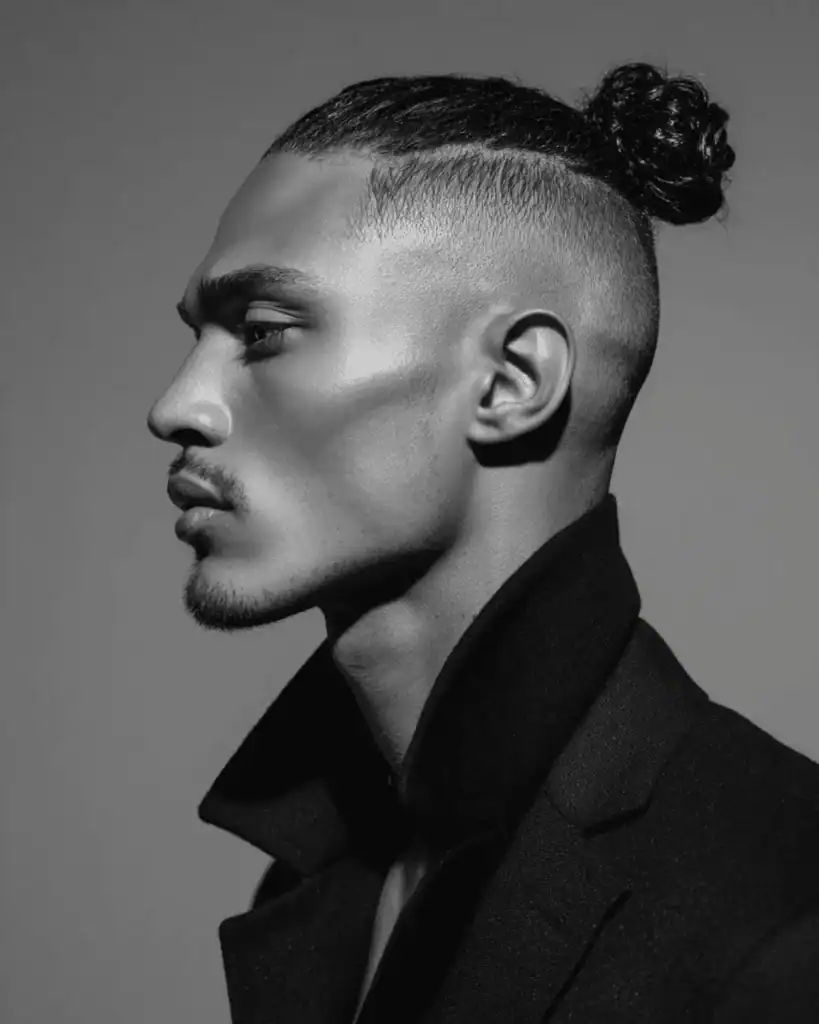 High fade top knot haircut for men with shaved sides and a tied bun on top